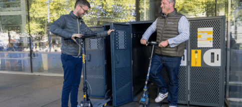 Personnes qui rangent une trottinette dans la Trottin'Box AbriPlus